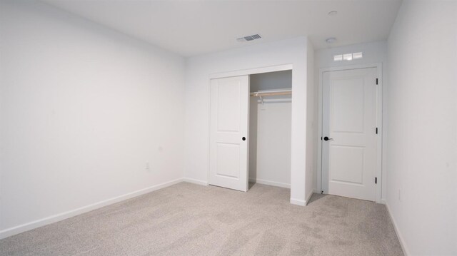 unfurnished bedroom with light colored carpet and a closet