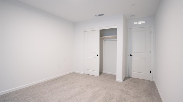 unfurnished bedroom featuring a closet and light colored carpet