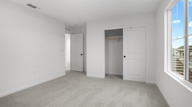 unfurnished bedroom featuring a closet and light colored carpet