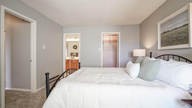 bedroom with a textured ceiling, ensuite bath, a closet, carpet, and baseboards