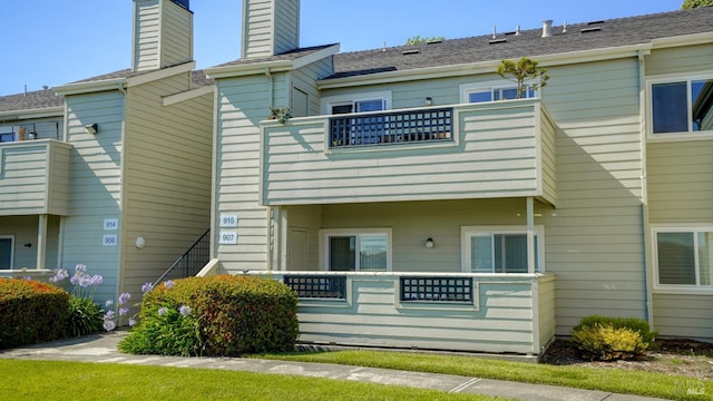 rear view of house featuring a balcony and a chimney