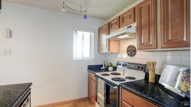 kitchen with under cabinet range hood, decorative backsplash, brown cabinets, and white range with electric cooktop