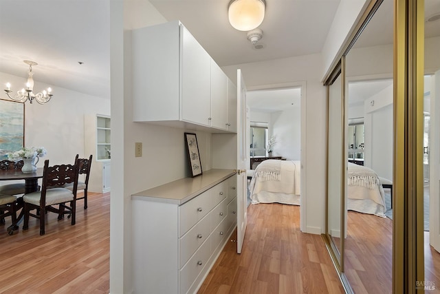 hall with light hardwood / wood-style floors and an inviting chandelier