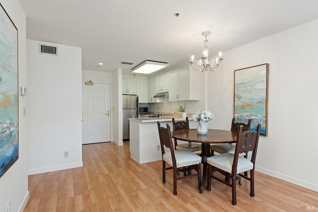 dining area with light hardwood / wood-style floors, a chandelier, and sink