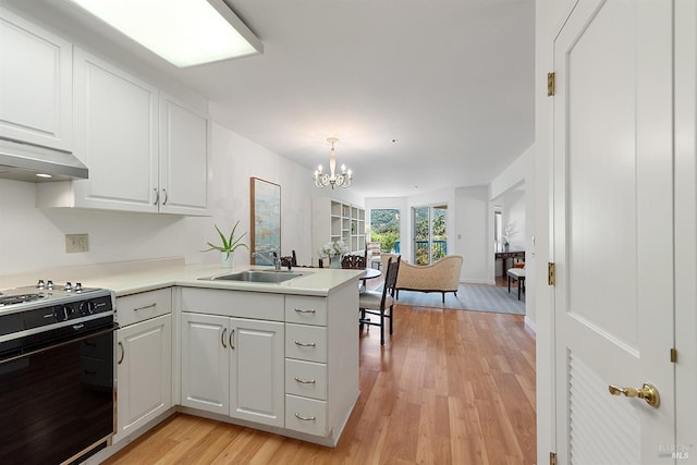 kitchen featuring kitchen peninsula, stove, hanging light fixtures, and white cabinets