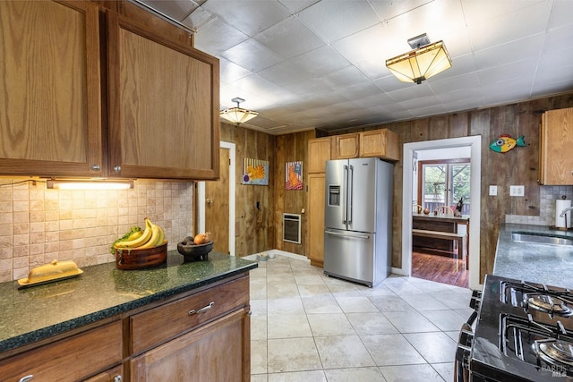 kitchen with black gas range, heating unit, light tile patterned floors, sink, and high end fridge