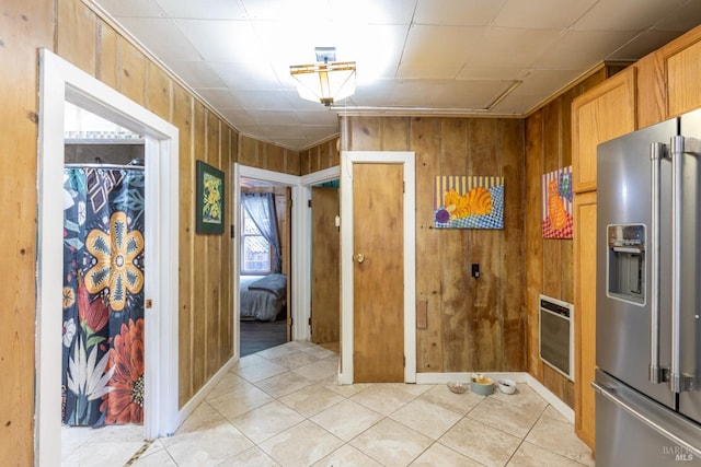 kitchen featuring high quality fridge, wood walls, light tile patterned flooring, and heating unit