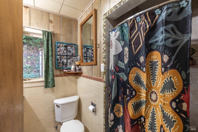 bathroom featuring toilet, tile walls, and a drop ceiling