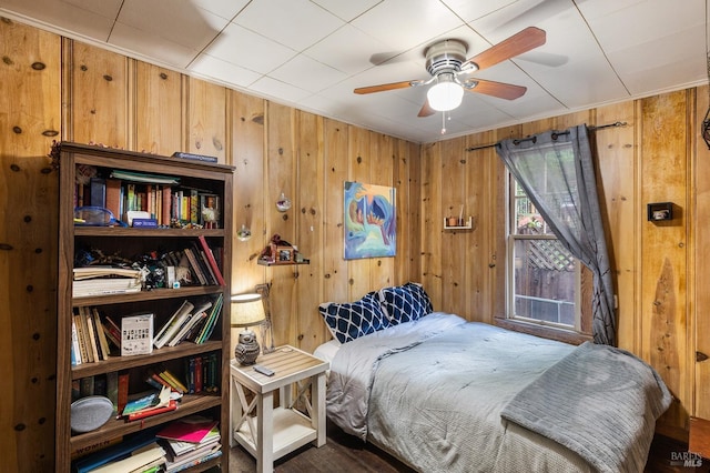 bedroom featuring ceiling fan and wooden walls