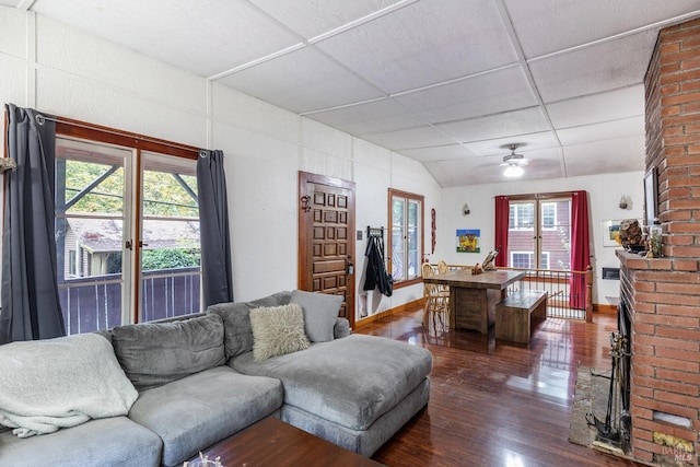 living room with dark wood-type flooring, ceiling fan, and a paneled ceiling