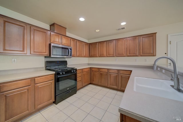 kitchen with black gas stove, light tile patterned floors, and sink