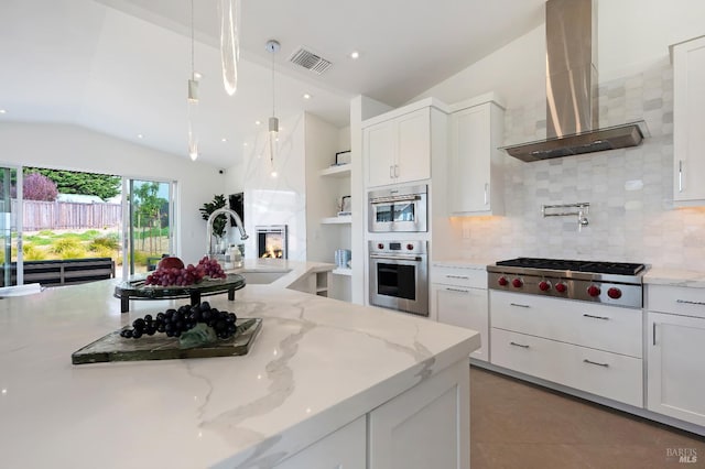 kitchen with wall chimney exhaust hood, sink, light stone counters, stainless steel gas stovetop, and white cabinets