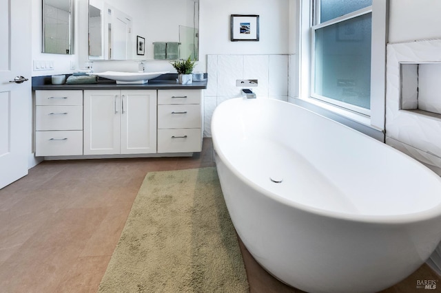 bathroom with tile patterned floors, vanity, tile walls, and a tub