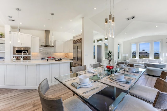 dining space featuring lofted ceiling, sink, and light hardwood / wood-style flooring