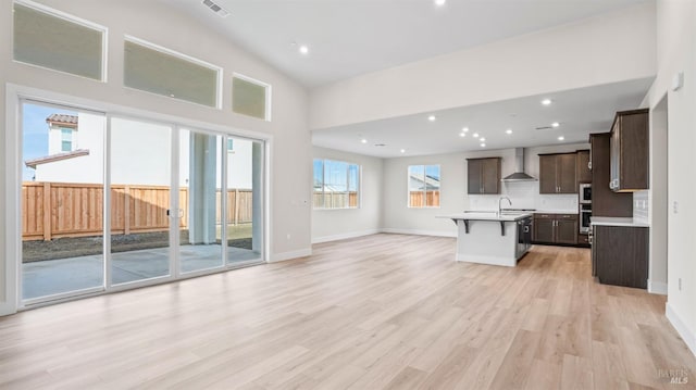 unfurnished living room with high vaulted ceiling and light wood-type flooring