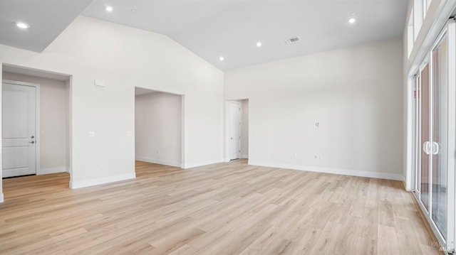 empty room with light wood-type flooring, high vaulted ceiling, and a wealth of natural light