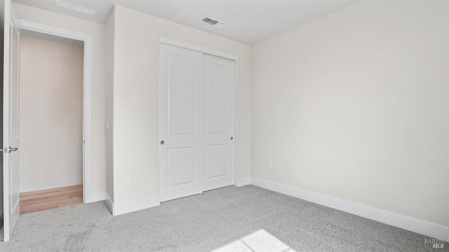 unfurnished bedroom with light carpet and a closet