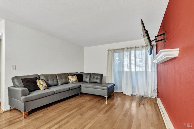 living room featuring a baseboard heating unit, a textured ceiling, and light hardwood / wood-style flooring