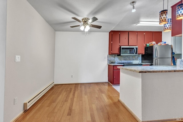 kitchen featuring a baseboard heating unit, light hardwood / wood-style flooring, decorative backsplash, a textured ceiling, and appliances with stainless steel finishes