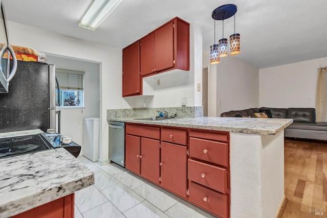 kitchen with appliances with stainless steel finishes, a textured ceiling, sink, light hardwood / wood-style flooring, and hanging light fixtures