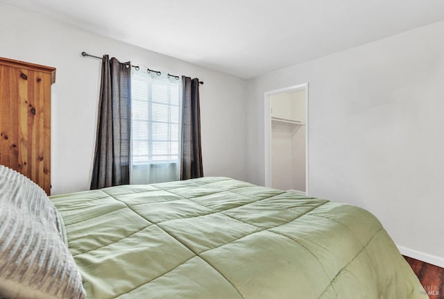 bedroom with a spacious closet, a closet, and hardwood / wood-style floors