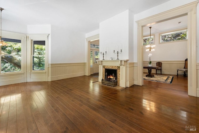 unfurnished living room featuring plenty of natural light, dark wood-type flooring, and a chandelier