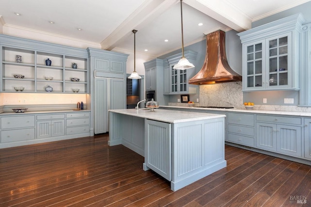 kitchen with premium range hood, hanging light fixtures, dark hardwood / wood-style flooring, an island with sink, and beamed ceiling