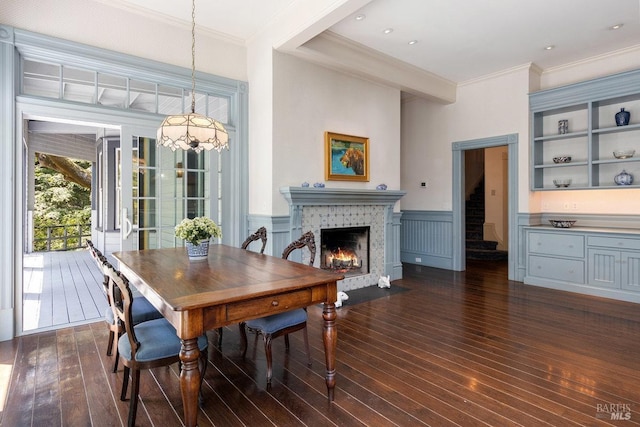 dining area featuring a tile fireplace, ornamental molding, and dark hardwood / wood-style flooring