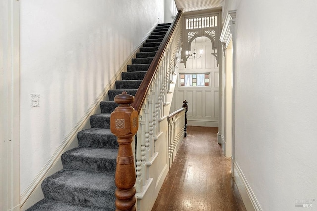 stairs with hardwood / wood-style floors and a notable chandelier