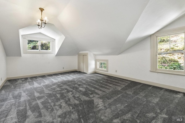 bonus room featuring vaulted ceiling, a notable chandelier, and dark carpet