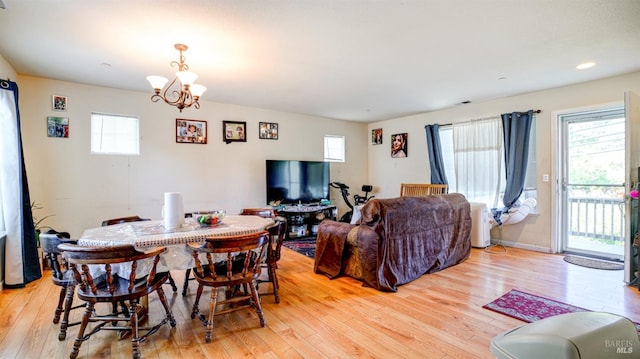 dining area with light wood-type flooring, a notable chandelier, and baseboards