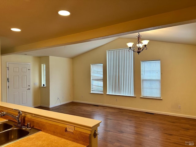 kitchen featuring dark wood-type flooring, decorative light fixtures, vaulted ceiling, a sink, and recessed lighting