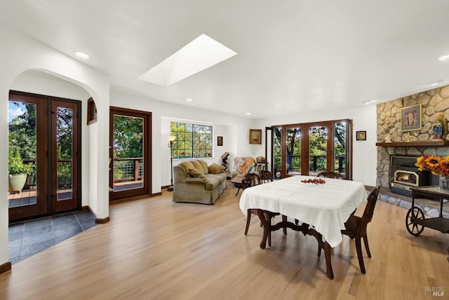 dining area featuring french doors, a skylight, and light hardwood / wood-style flooring