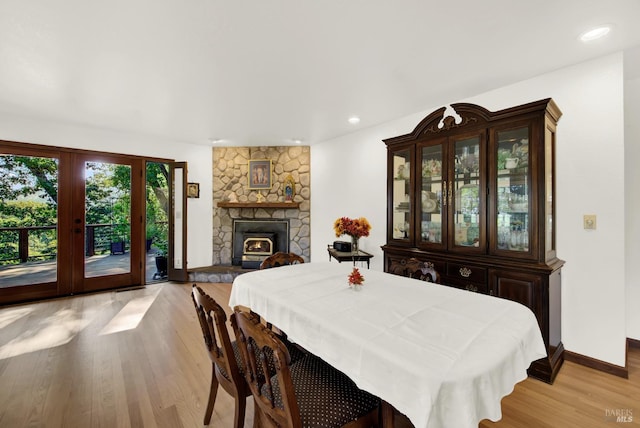 dining area with a stone fireplace and light hardwood / wood-style flooring