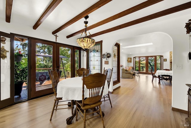 dining room with beamed ceiling, light hardwood / wood-style flooring, and french doors