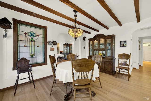 dining area featuring beamed ceiling and light hardwood / wood-style floors