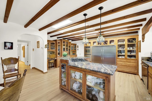 kitchen featuring a center island, light hardwood / wood-style flooring, appliances with stainless steel finishes, pendant lighting, and dark stone counters