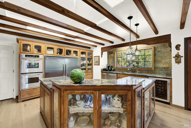 kitchen with appliances with stainless steel finishes, a center island, dark stone counters, and decorative light fixtures