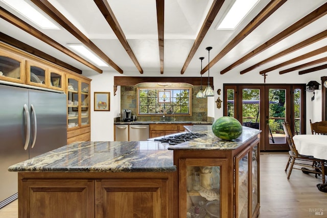 kitchen with appliances with stainless steel finishes, decorative light fixtures, a center island, and dark stone countertops