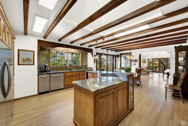 kitchen with stainless steel appliances, dark stone countertops, light wood-type flooring, and decorative light fixtures