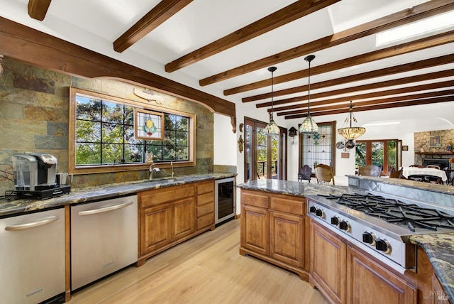 kitchen featuring pendant lighting, sink, dark stone countertops, wine cooler, and stainless steel appliances