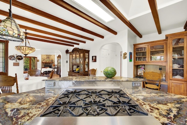 kitchen featuring pendant lighting, dark stone counters, and beamed ceiling