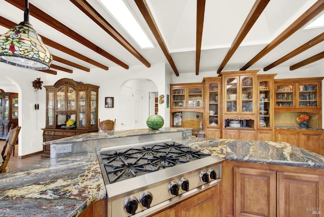 kitchen featuring hanging light fixtures, stainless steel gas cooktop, beam ceiling, and dark stone counters