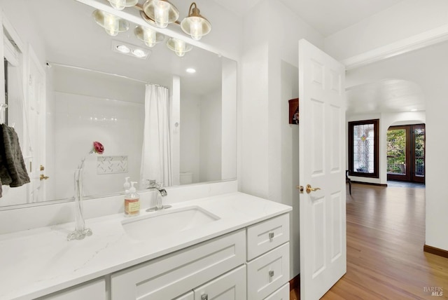 bathroom featuring hardwood / wood-style flooring, vanity, french doors, toilet, and walk in shower