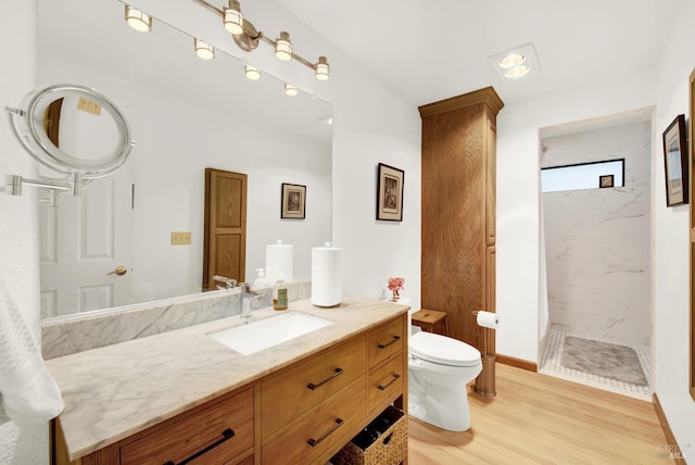 bathroom with vanity, hardwood / wood-style floors, toilet, and a tile shower