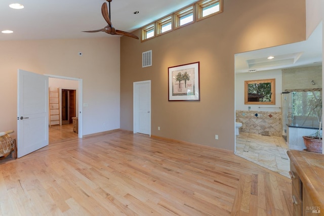 unfurnished living room with a towering ceiling, light wood finished floors, visible vents, and recessed lighting