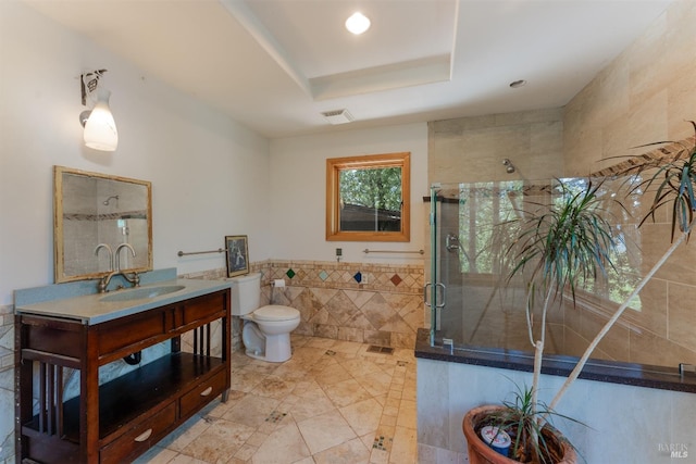 bathroom featuring toilet, a sink, visible vents, tile walls, and a raised ceiling