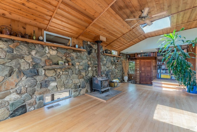 unfurnished living room with visible vents, lofted ceiling, wooden ceiling, wood finished floors, and a wood stove