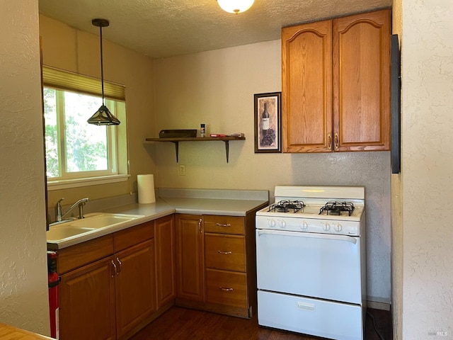 kitchen featuring decorative light fixtures, a textured ceiling, dark hardwood / wood-style floors, and white gas range oven