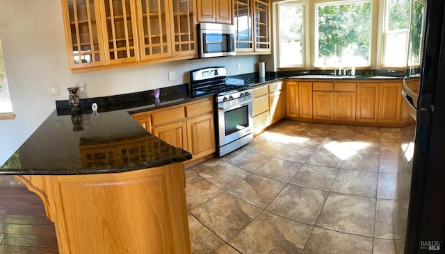 kitchen with dark stone countertops, kitchen peninsula, a breakfast bar area, and stainless steel appliances